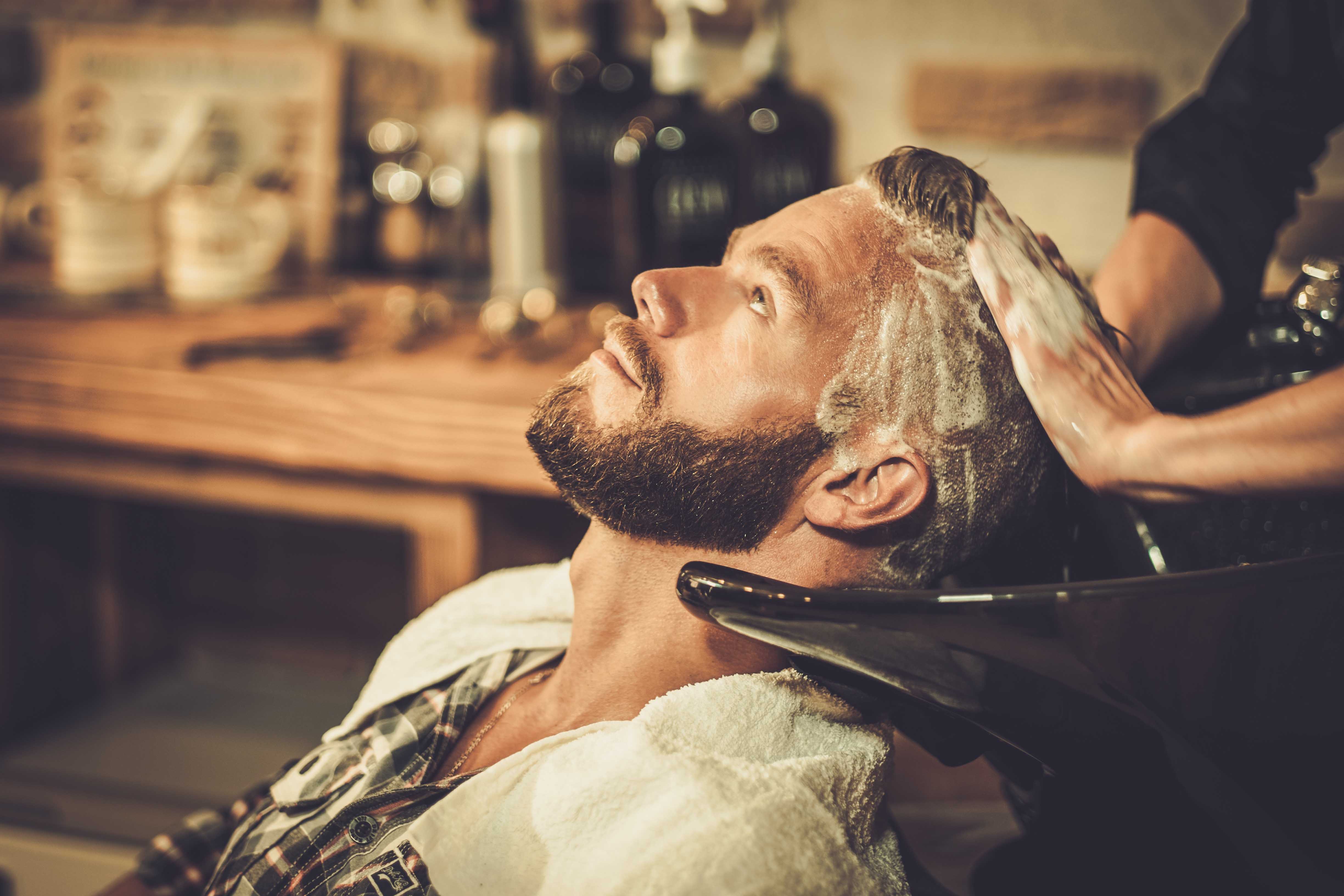 Hairstylist washing client's hair in barber shop